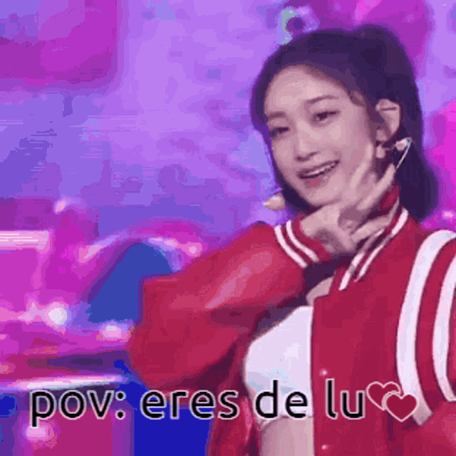 a woman in a red jacket is smiling and making a face with her hand .