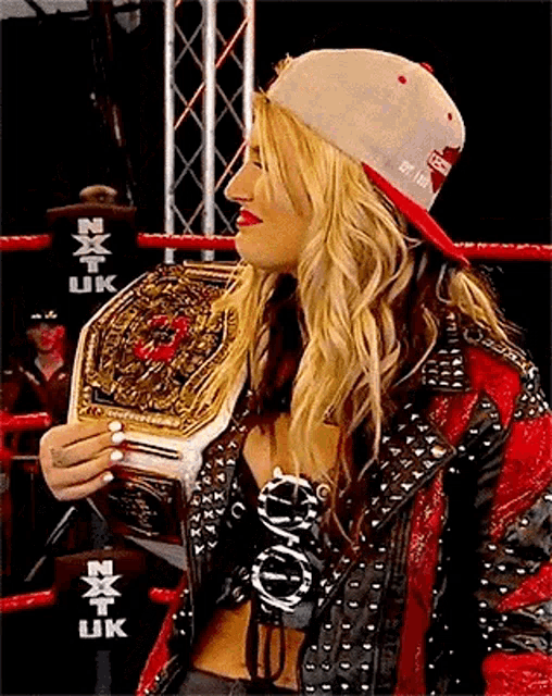 a woman is holding a championship belt in a wrestling ring .