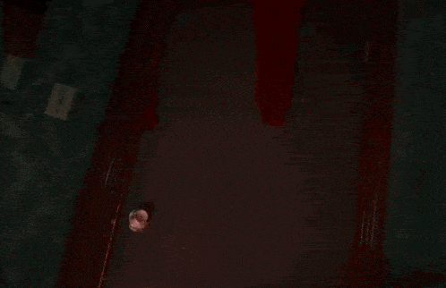 a person is standing in a doorway with a red light behind them holding a knife .