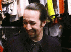 a man is standing in front of a closet with clothes hanging on the racks .