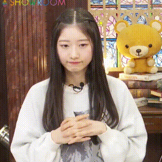 a girl is standing in front of a teddy bear and books .