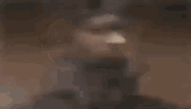 a close up of a man 's face with his mouth open and a blurred background .