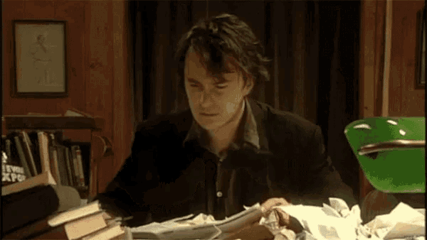 a man is sitting at a desk with books and papers on it .
