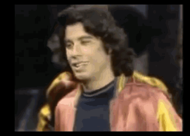 a man in a red and yellow jacket is smiling and looking at the camera