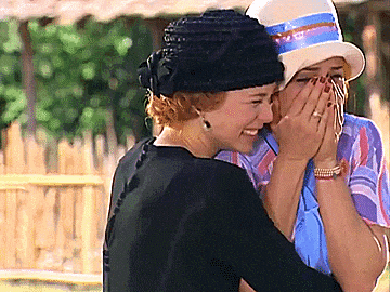 two women wearing hats are hugging each other and one is covering her face