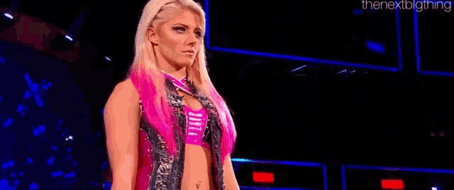 a woman in a pink and black outfit is standing on a stage in front of a crowd .