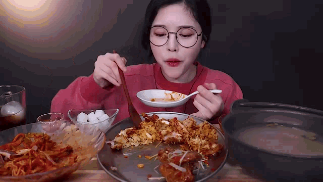 a woman wearing glasses is eating a plate of food with a spoon