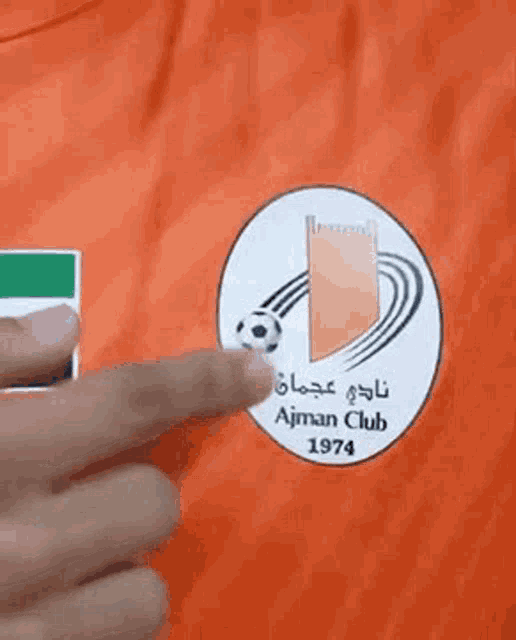 a person is pointing at a soccer ball on a jersey .