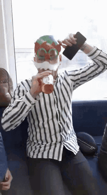 a man wearing a santa mask is drinking a soda