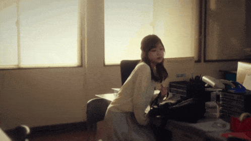 a woman sits at a desk in front of a window with a sticker on the wall that says ' samsung ' on it