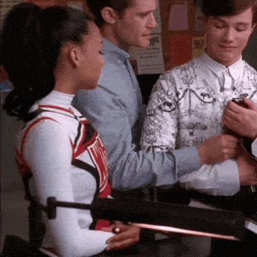 a woman in a cheerleading uniform talks to a man and another man