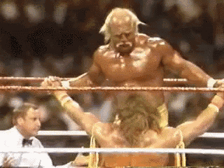 a man is standing in a boxing ring with his arms outstretched while another man stands behind him .