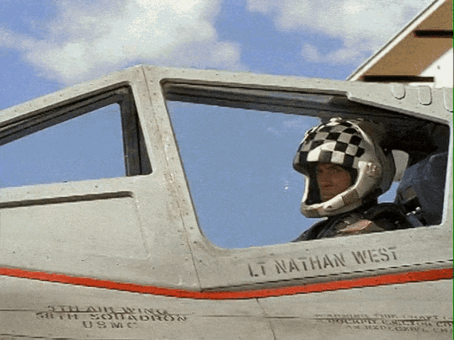 a man in a helmet sits in the cockpit of a plane with the name lt nathan west on the side