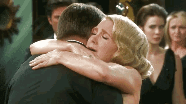 a woman in a black dress is hugging a man in a black tuxedo