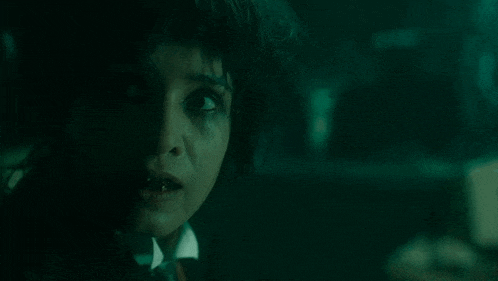 a close up of a woman 's face in a dark room with a scary look on her face .