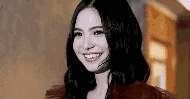 a woman is smiling in a black and white photo while wearing a red dress .