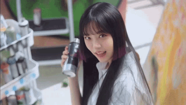 a woman with long black hair is holding a bottle in her hand