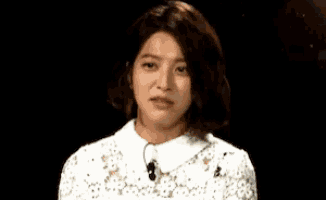 a woman in a white dress is making a funny face while wearing a microphone .
