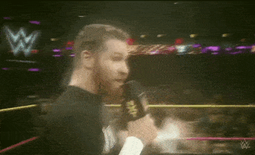 a man is talking into a microphone in a wrestling ring
