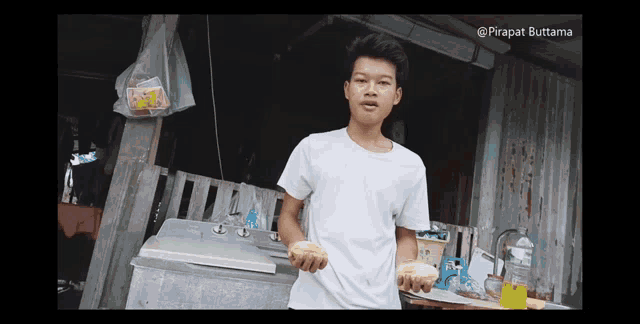 a young man in a white shirt is holding a piece of food in front of a washing machine