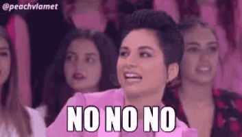 a woman in a pink shirt is sitting in front of a group of women and says no no no .