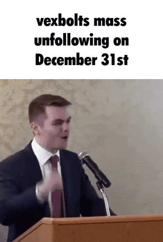 a man in a suit and tie is speaking into a microphone with the words vexbolts mass unfollowing