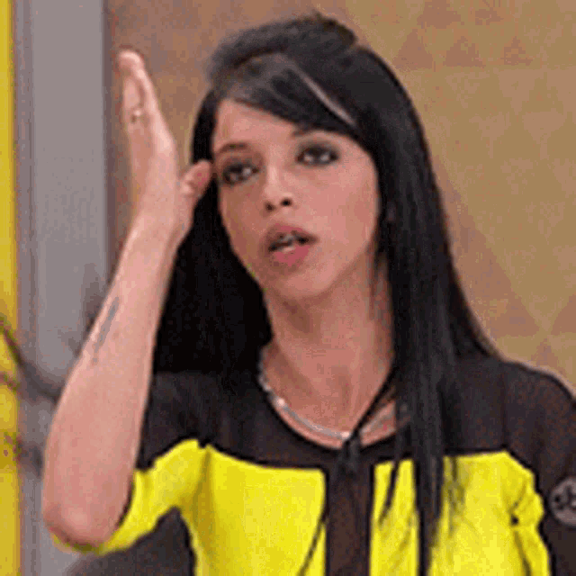 a woman in a yellow and black shirt is making a funny face