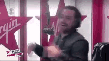 a man with a beard is dancing in front of a microphone in a radio studio .