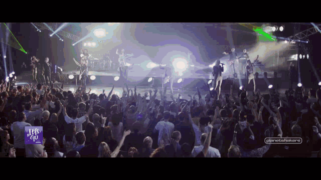 a crowd of people at a concert with a sign that says ' let 's go ' in the corner