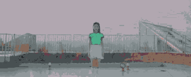 a woman in a green shirt is standing in front of a building with her eyes closed .