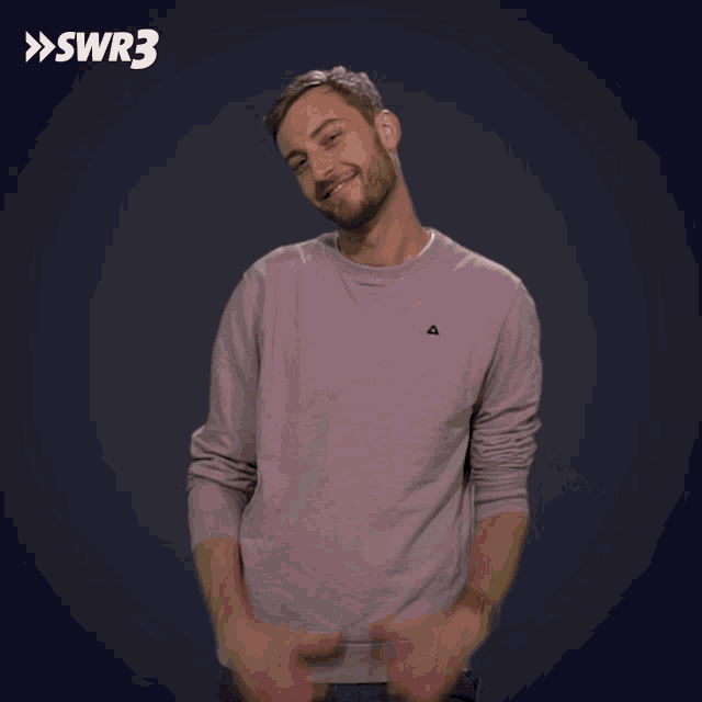 a man wearing a pink sweater with a small triangle on the chest