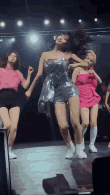 a group of girls are dancing on a stage in a concert .