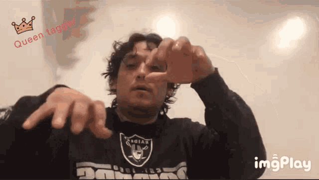 a man wearing a raiders shirt is making a gesture