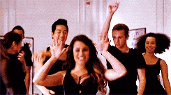 a group of people are dancing in a room and one woman is waving