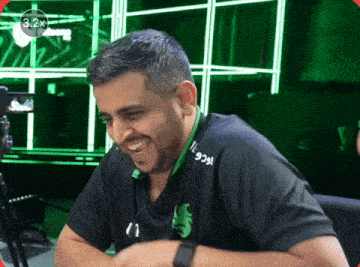 a man wearing a black shirt that says 929 on it smiles in front of a green background