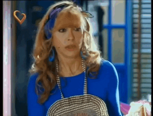 a woman in a blue dress and apron is standing in front of a window .