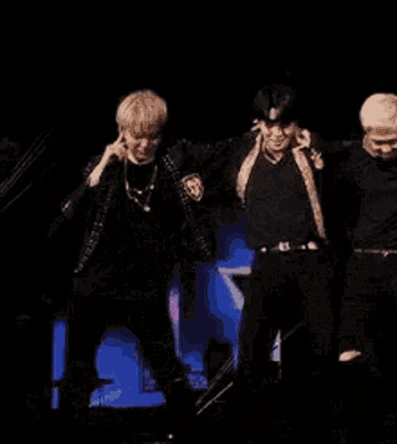 a group of young men are standing on a stage holding microphones and dancing .