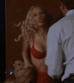a man and a woman are standing next to each other in a room . the woman is wearing a red bra .