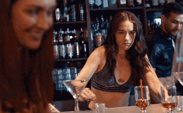 a woman sits at a bar with a martini glass in her hand