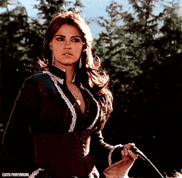 a woman is holding a whip in front of trees and the words edits portibironi are on the bottom