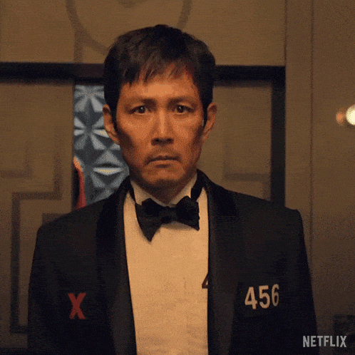 a man in a tuxedo and bow tie has the number 456 on his shirt .