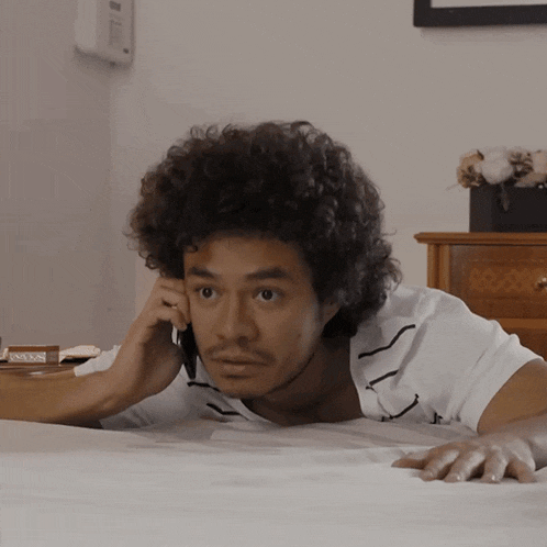 a man laying on a bed talking on his cell phone
