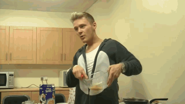 a man prepares cereal in a kitchen with a box of kellogg 's flakes