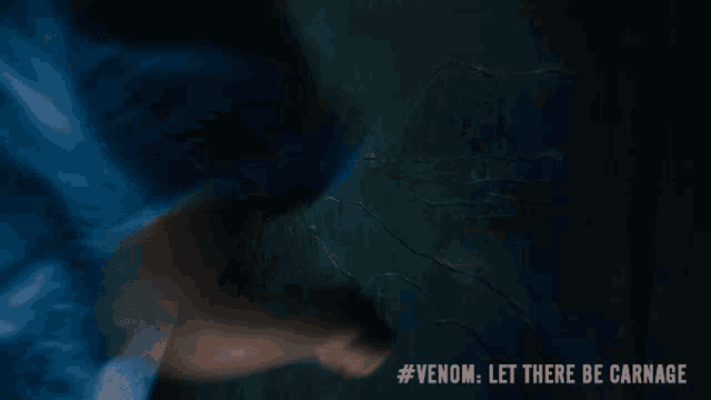 a woman in a blue shirt is running in a dark room with the words #venom let there be carnage written on the bottom