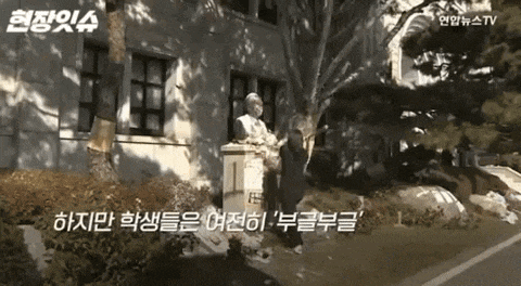 a statue of a man standing in front of a building with foreign writing