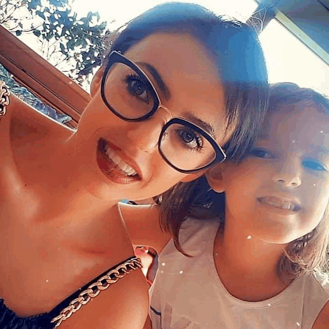 a woman wearing glasses is posing for a picture with her daughter .