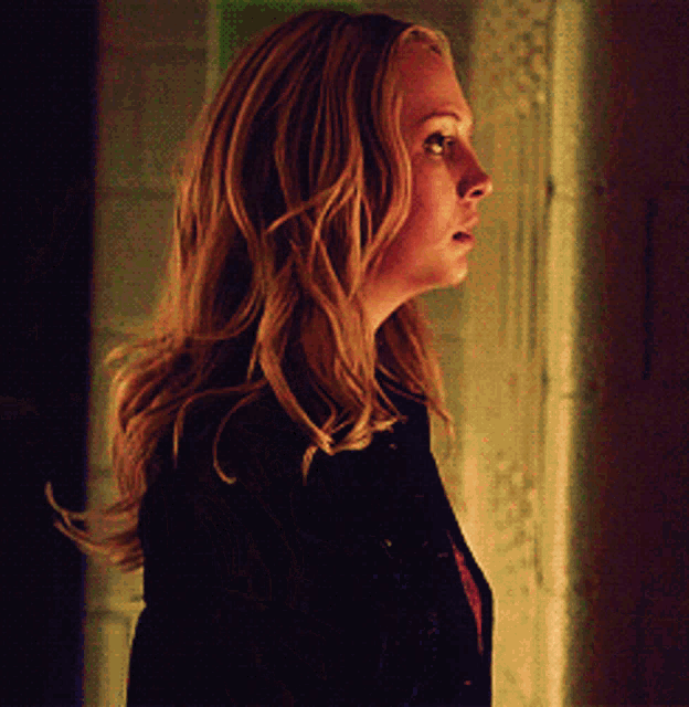 a woman with blonde hair is standing in the dark