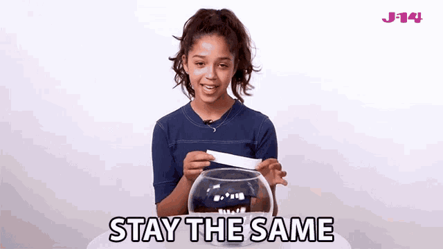 a girl is holding a piece of paper in front of a fish bowl with the words stay the same on the bottom