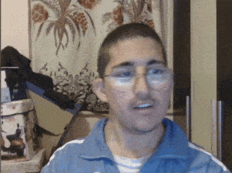 a man wearing glasses and a blue jacket stands in front of a box that says oasis