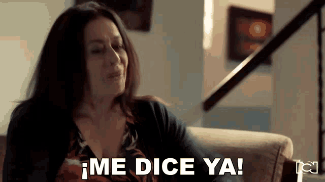 a woman is sitting on a couch and says me dice ya !
